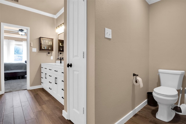 bathroom with crown molding, wood-type flooring, toilet, and vanity