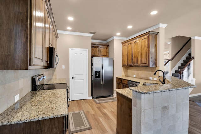 kitchen featuring sink, light hardwood / wood-style flooring, kitchen peninsula, stainless steel appliances, and light stone countertops