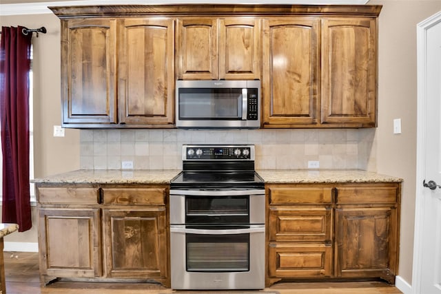 kitchen featuring tasteful backsplash, appliances with stainless steel finishes, and light stone countertops