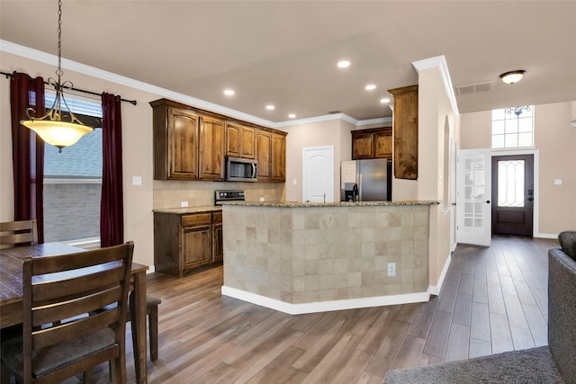 kitchen with backsplash, hardwood / wood-style flooring, light stone countertops, and appliances with stainless steel finishes