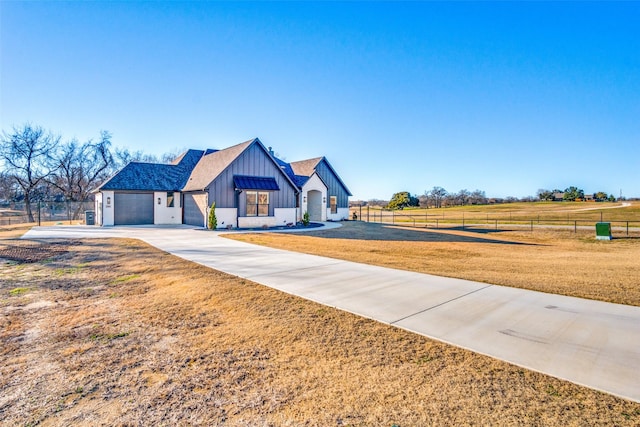 modern farmhouse featuring a garage, a front yard, and a rural view