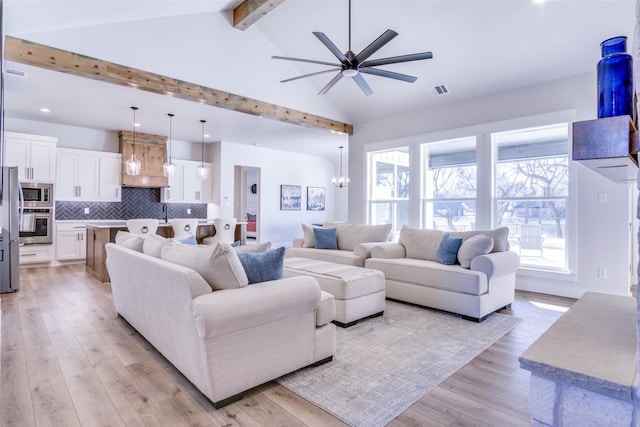 living room featuring ceiling fan with notable chandelier, high vaulted ceiling, sink, light hardwood / wood-style floors, and beam ceiling