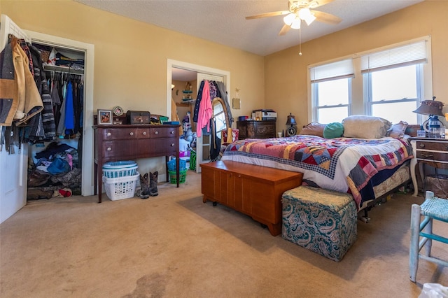 bedroom with a ceiling fan, a closet, light colored carpet, and a textured ceiling