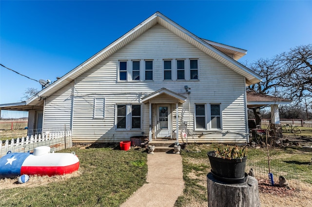 view of front of home featuring entry steps, fence, and a front yard