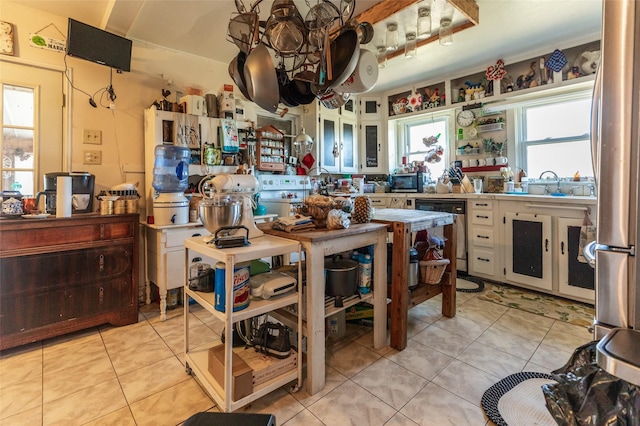 kitchen featuring stainless steel appliances, white cabinets, light tile patterned flooring, and a sink