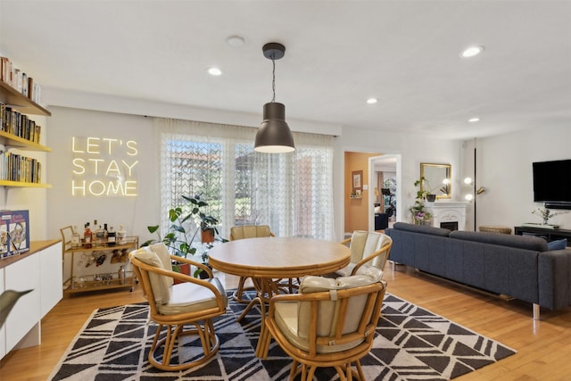 dining area featuring a fireplace, recessed lighting, and light wood-style floors