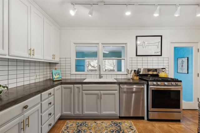 kitchen with tasteful backsplash, ornamental molding, appliances with stainless steel finishes, light tile patterned flooring, and a sink