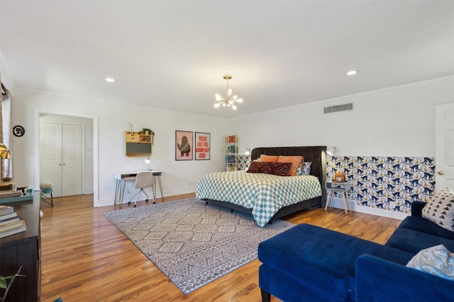 bedroom featuring wood finished floors, visible vents, baseboards, crown molding, and a notable chandelier