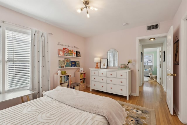 bedroom with visible vents, multiple windows, baseboards, and light wood-style flooring