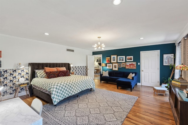 bedroom with visible vents, ornamental molding, an inviting chandelier, and wood finished floors