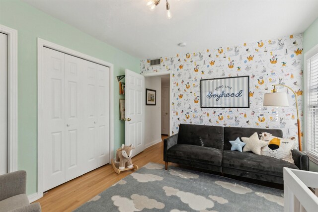 living room with wallpapered walls, wood finished floors, and visible vents