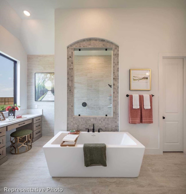 bathroom featuring lofted ceiling, vanity, shower with separate bathtub, and tile walls