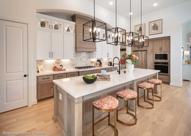 kitchen featuring a breakfast bar, decorative light fixtures, appliances with stainless steel finishes, a large island, and white cabinets