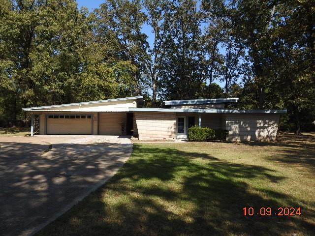 single story home featuring a garage and a front lawn