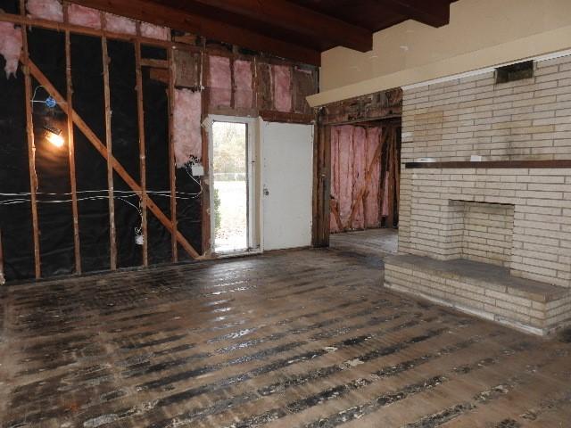 unfurnished living room featuring dark hardwood / wood-style floors and beam ceiling