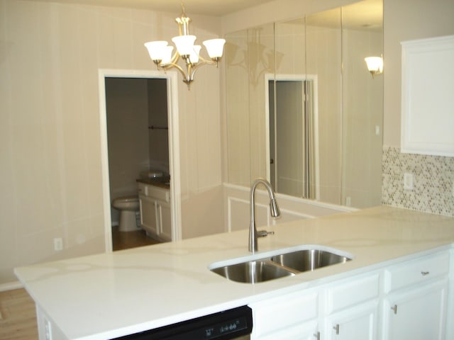 kitchen featuring pendant lighting, sink, white cabinetry, and backsplash