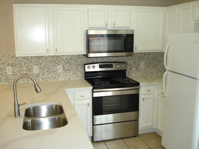 kitchen with sink, white cabinetry, light tile patterned floors, stainless steel appliances, and decorative backsplash