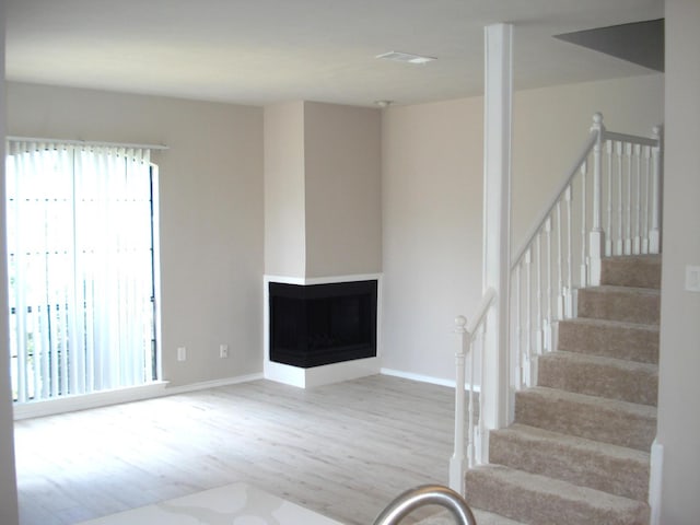 staircase with hardwood / wood-style flooring and a multi sided fireplace