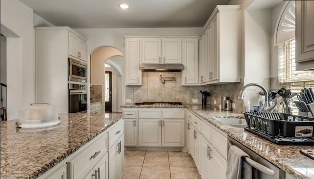 kitchen featuring white cabinetry, stainless steel appliances, light stone countertops, and sink