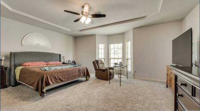 carpeted bedroom featuring ceiling fan and a tray ceiling