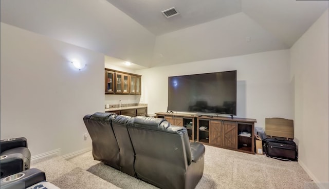 carpeted home theater room featuring bar area and vaulted ceiling