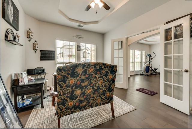 sitting room featuring a raised ceiling, dark wood-type flooring, ceiling fan, and french doors