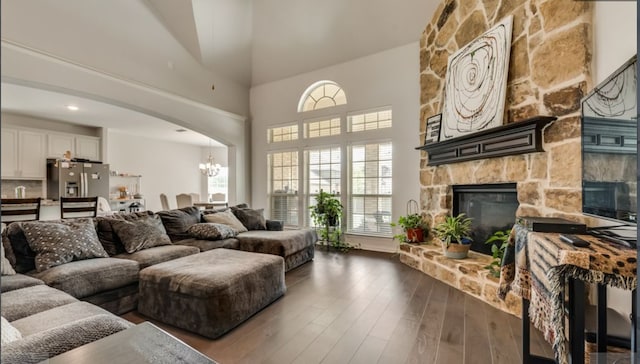 living room with dark hardwood / wood-style floors, a towering ceiling, a fireplace, and a chandelier