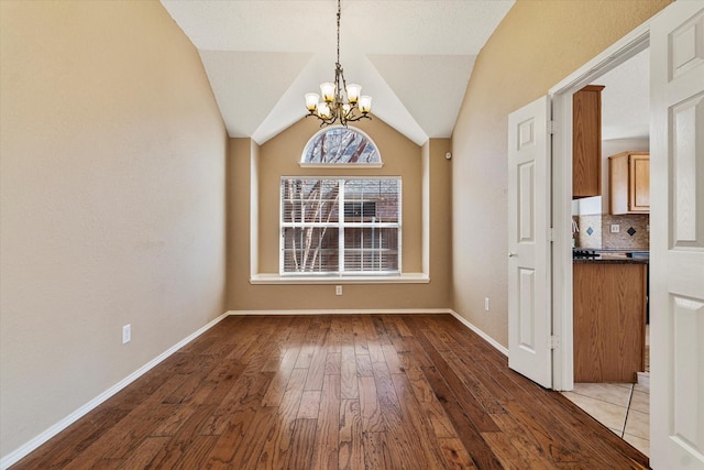 unfurnished dining area with lofted ceiling, wood-type flooring, and a notable chandelier