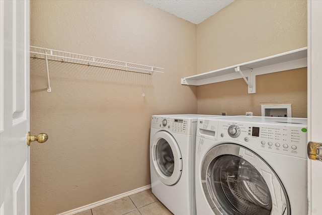 clothes washing area with washing machine and dryer and light tile patterned floors