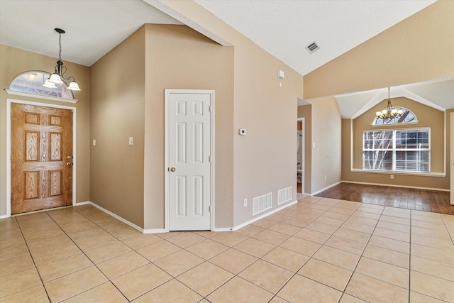 tiled entryway with high vaulted ceiling and a chandelier