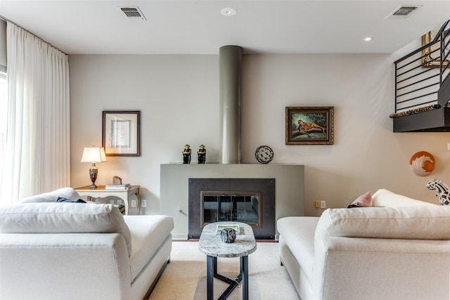 carpeted living area featuring visible vents, a glass covered fireplace, a wealth of natural light, and recessed lighting