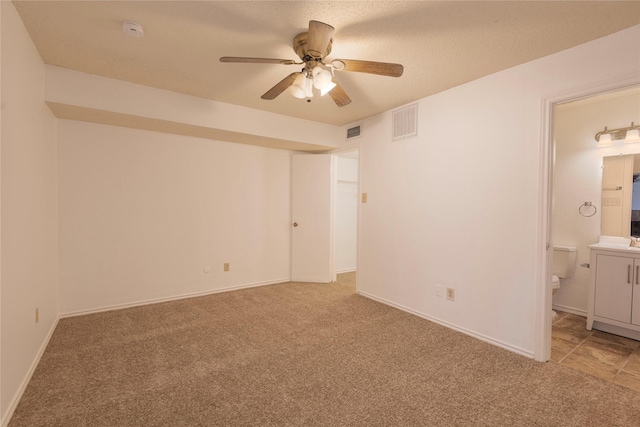 unfurnished bedroom with ceiling fan, ensuite bath, and carpet