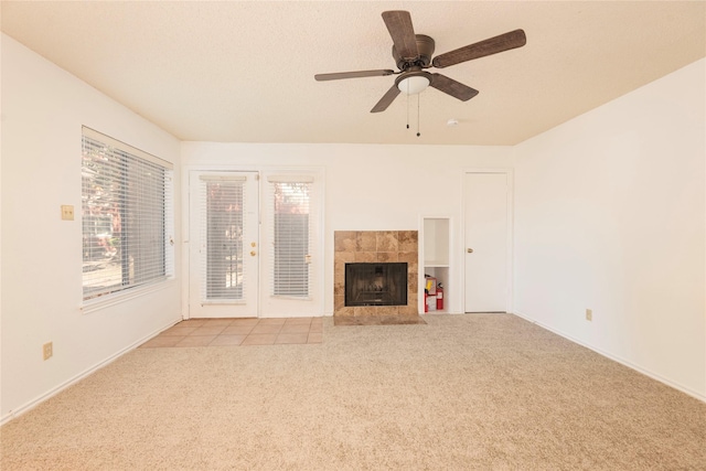 unfurnished living room with light carpet, ceiling fan, a fireplace, and a textured ceiling