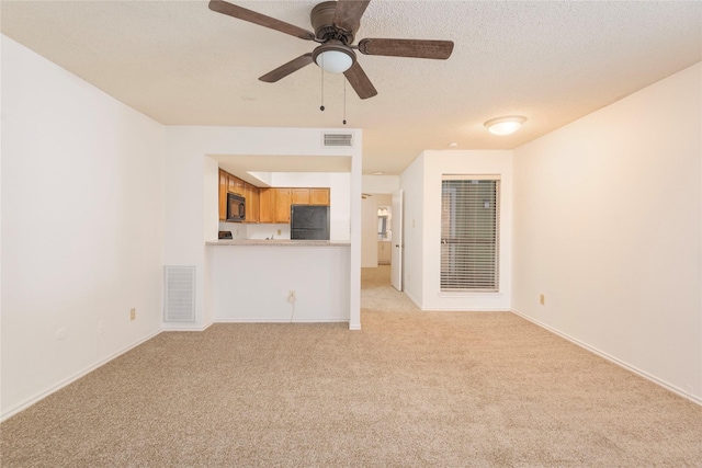 unfurnished living room featuring ceiling fan, light colored carpet, and a textured ceiling