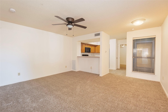 unfurnished living room with ceiling fan, light colored carpet, and a textured ceiling