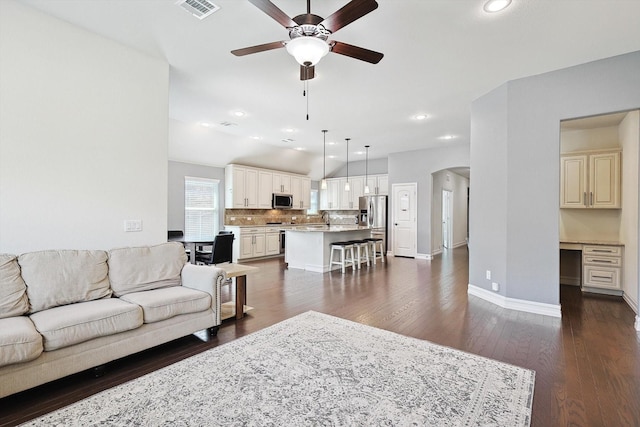 living room featuring sink, built in desk, vaulted ceiling, dark hardwood / wood-style flooring, and ceiling fan