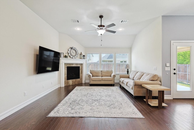 living room featuring a tile fireplace, a healthy amount of sunlight, vaulted ceiling, and dark hardwood / wood-style floors