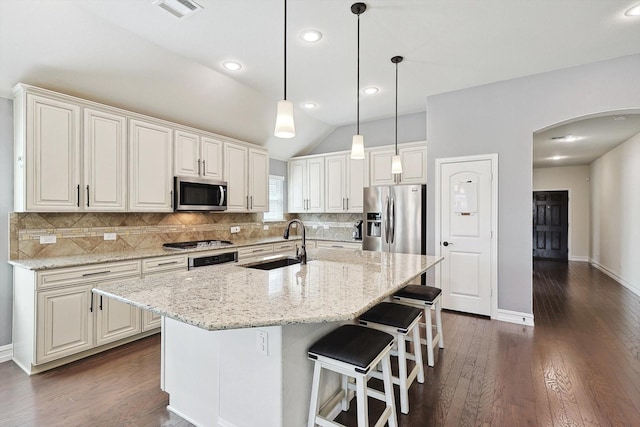 kitchen featuring sink, white cabinetry, stainless steel appliances, light stone countertops, and an island with sink