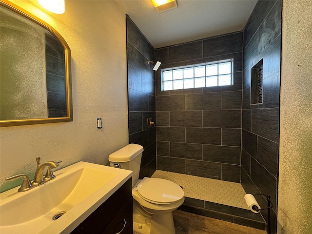 bathroom with vanity, toilet, and a tile shower