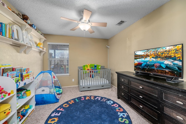 carpeted bedroom featuring ceiling fan and a textured ceiling