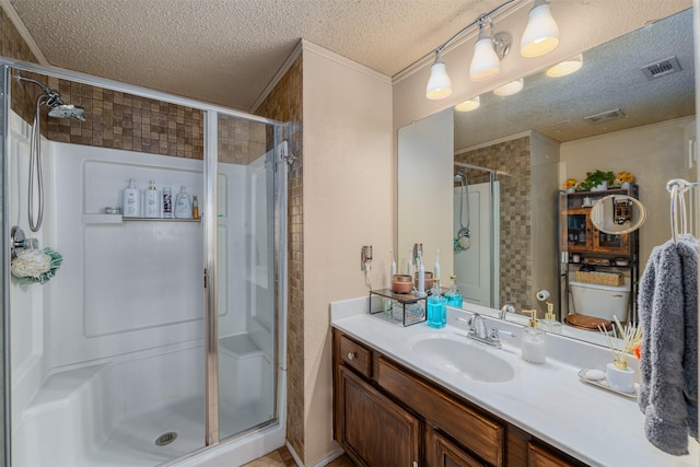 bathroom with vanity, a shower with door, and a textured ceiling