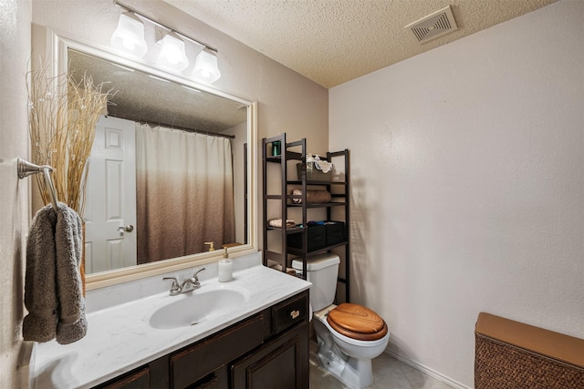 bathroom featuring tile patterned flooring, vanity, a textured ceiling, and toilet