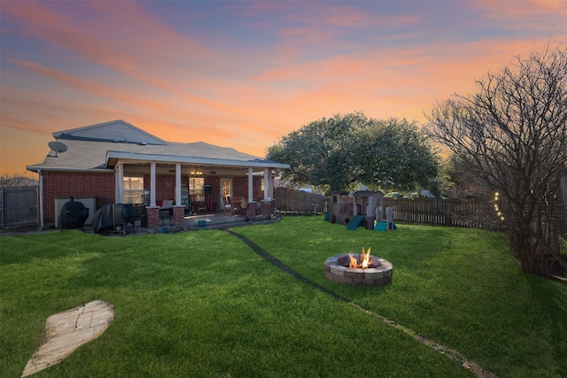 yard at dusk featuring a playground, a patio, and an outdoor fire pit