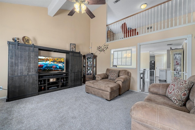 carpeted living room featuring beamed ceiling, a barn door, a towering ceiling, and ceiling fan