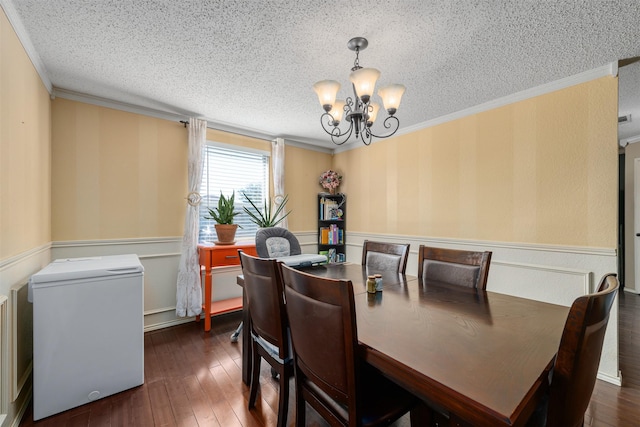 dining space featuring dark hardwood / wood-style flooring, crown molding, a textured ceiling, and an inviting chandelier