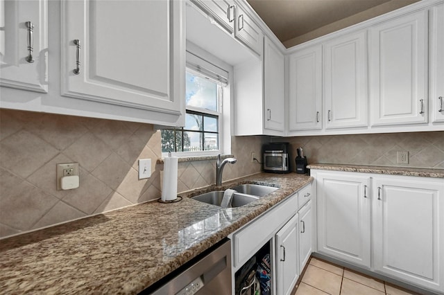 kitchen with light tile patterned flooring, sink, white cabinetry, tasteful backsplash, and stone counters