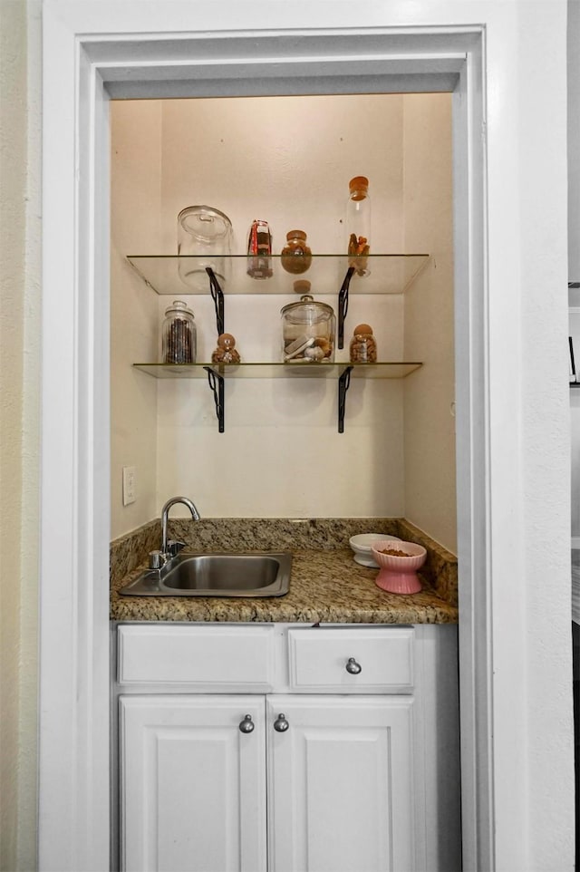 bar with sink, dark stone countertops, and white cabinets