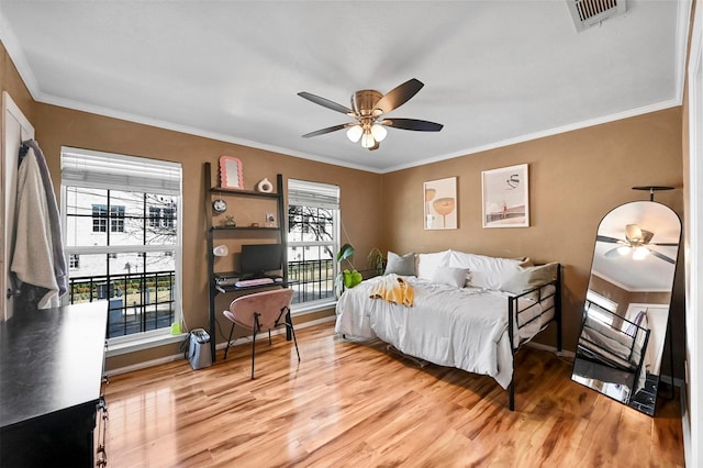 bedroom featuring ceiling fan, ornamental molding, and light hardwood / wood-style flooring