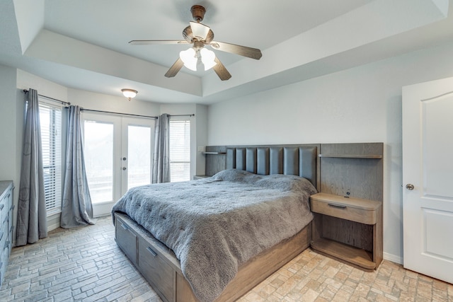 bedroom with access to exterior, a raised ceiling, ceiling fan, and french doors