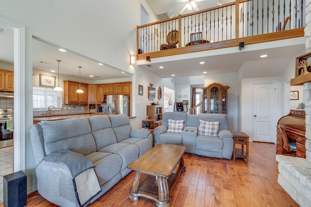 living room featuring sink, a towering ceiling, a wealth of natural light, and light hardwood / wood-style floors